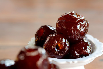 Sweet Jujube or Chinese red date in syrup in white Thai style cup on wood table and space for write wording, Clever idea for fresh fruit preservation, popular sweet, unhealthy food cause of disease
