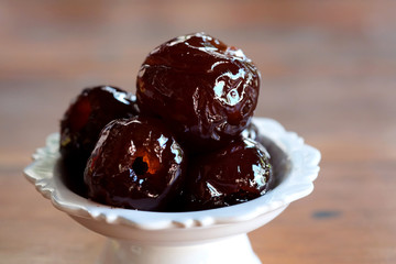 Sweet Jujube or Chinese red date in syrup in white Thai style cup on wood table and space for write wording, Clever idea for fresh fruit preservation, popular sweet, unhealthy food cause of disease