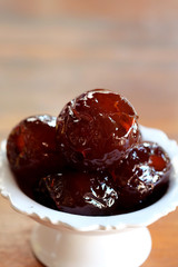 Sweet Jujube or Chinese red date in syrup in white Thai style cup on wood table and space for write wording, Clever idea for fresh fruit preservation, popular sweet, unhealthy food cause of disease