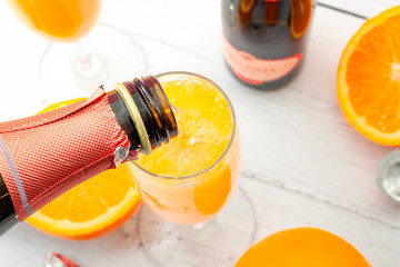 Lush mix drinks, summer alcoholic beverages and refreshing brunch mimosa cocktail concept with top view of orange fruits and champagne pouring from bottle of bubbly isolated on wooden table background - obrazy, fototapety, plakaty