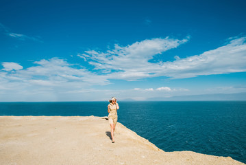 Woman in sunglasses walks on the rocky coast of the Dead Sea