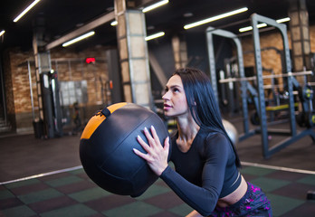 Concentrated fit woman in sportswear doing exercise with med ball in gym