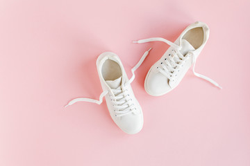 White female sneakers on pink background. Flat lay, top view minimal background. Fashion blog or...