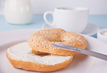 Fresh healthy bagel on a white napkin with cup of coffee, cream cheese and eggs for breakfast.