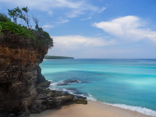 Turquoise waves crash against stones with splashes. Bali.