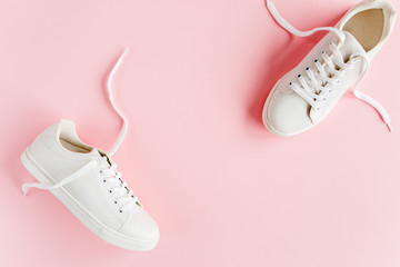 White female sneakers on pink background. Flat lay, top view minimal background. Fashion blog or magazine concept.