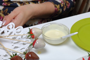 Strawberry glazed with dark and white chocolate dries on a plate. Cooking strawberries glazed in chocolate.