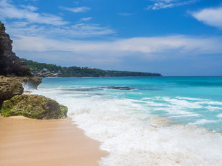 Turquoise waves crash against stones with splashes. Bali.