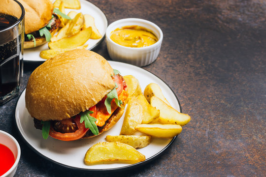 An American Burger With Fried Potatoes On The White Plate.