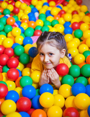 Happy little girl playing and having fun at kindergarten with colorful balls in play center