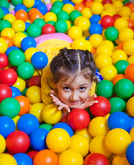 Fototapeta na wymiar Happy little girl playing and having fun at kindergarten with colorful balls in play center