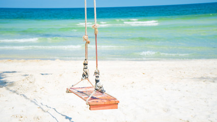 Swing on the beautiful beach with white sand and crystal clear blue water background for tourism...