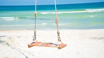 Swing on the beautiful beach with white sand and crystal clear blue water background for tourism concept