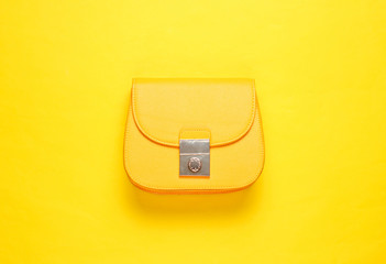 Yellow leather mini bag on yellow background. Minimalism fashion concept. Top view