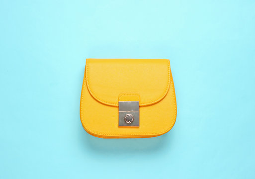 Yellow leather mini bag on blue background. Minimalism fashion concept. Top view