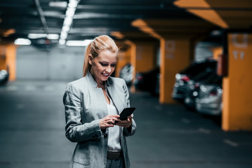 Successful woman using phone in underground parking.
