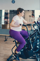 Fototapeta na wymiar Fat woman intensely exercising on stationary bike