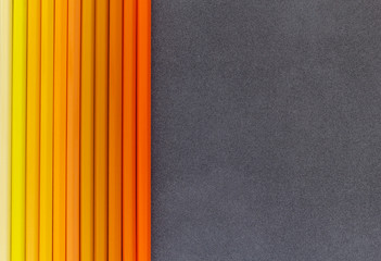 Yellow and orange colored pencils on dark background top view
