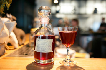 Bottle and glass filled with red alcoholic drink on the bar counter. bottle with space for your text