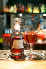 Bottle and glass filled with red alcoholic drink on the bar counter. bottle with space for your text