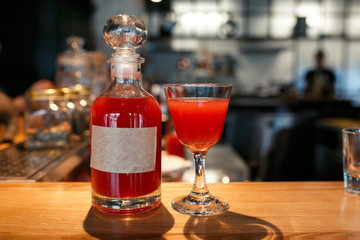 Bottle and glass filled with red alcoholic drink on the bar counter. bottle with space for your text
