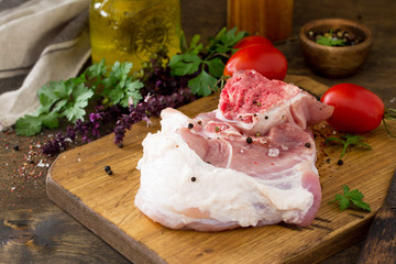 Fresh raw meat. Raw pork meat steak with olive oil, tomatoes and herbs on wooden table. Copy space.