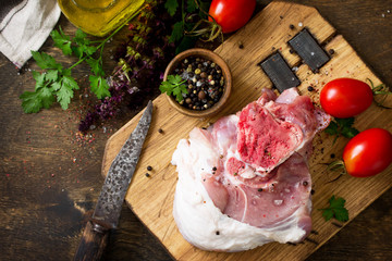 Fresh raw meat. Raw pork meat steak with olive oil, tomatoes and herbs on wooden table. Top view flat lay background with copy space.