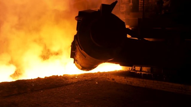 Molten steel pouring process with steam clubs at metallurgical plant. Stock footage. Close up fot steel pouring machine.