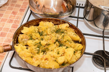 Fried potatoes with dill in a pan on gas stove