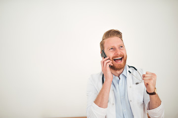 Doctor celebrating success while talking on phone.