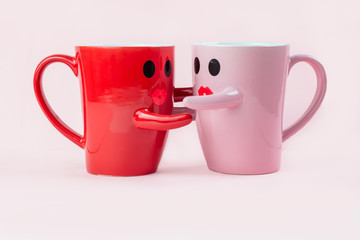 Friday's happy word. Two cups of coffee on a pink background with a smile face to the mug, hugging each other. The concept of love and relationships. Creative colorful greeting card