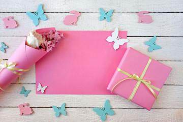 Różowo-białe tło z pudełkiem przewiązanym wstążką, kwiatami, zajączkami i motylami - obrazy, fototapety, plakaty