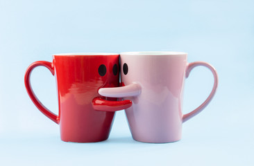 Friday's happy word. Two cups of coffee on a blue background with a smile facing the mug, hugging each other. The concept of love and relationships. Creative colorful greeting card