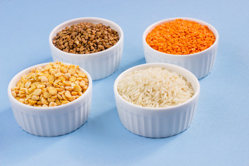 Assorted different cereals on a blue background. Buckwheat, lentils, rice, peas in plates on top, copy of the place. Healthy eating concept