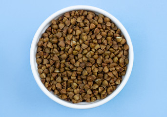 buckwheat in a plate on top, on a blue background, copy space