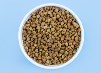 buckwheat in a plate on top, on a blue background, copy space