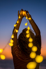 Romantic woman viewed from back with lot of yellow lights - emotion and wanderlust concept for people enojying romance and outdoor leisure - night shot with artificial light