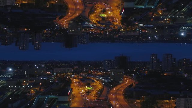 Aerial night view of a big city and beautiful lights, night life concept, mirror horizon effect. Media. Night cityscape with lighted roads and moving cars, inception theme.