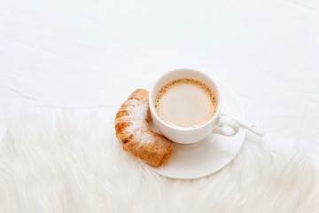 Cup of coffee on bed with warm plaid. Copy space. Flat lay, top view. Orange jam bagels. 