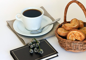 A cup of coffee with cookies and a volume of poemson the table