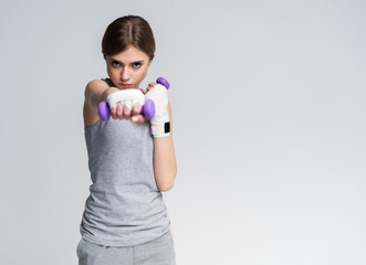 Portrait of pretty sporty girl holding weights dumbbells and make exercises.