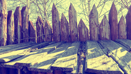 Fence made of sharp wooden stakes against the sky. Ancient stockade. Toned.