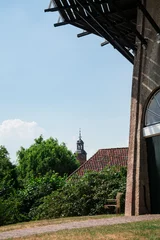 Fototapeten door of mill De Prins van Oranje n Buren, tower of Sint Lambertuskerk in Buren, The Netherlands © Corinne