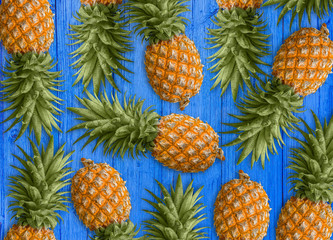 A lot of succulent pineapples on the blue wooden table. Healthy dietary food.