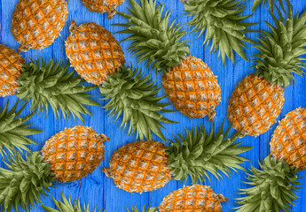 Fototapeta premium A lot of succulent pineapples on the blue wooden table. Healthy dietary food.