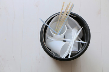 Disposable plastic dishes in the trash.