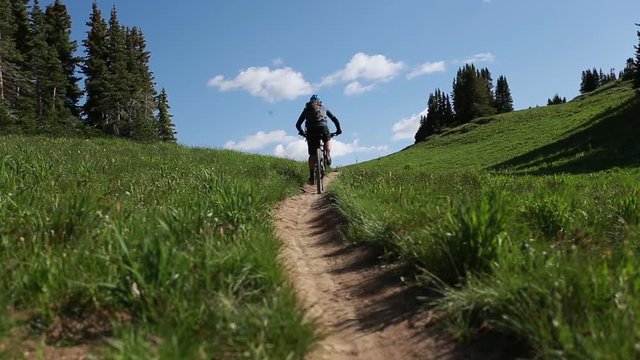 Mountain Biker Rides Up Dirt Path