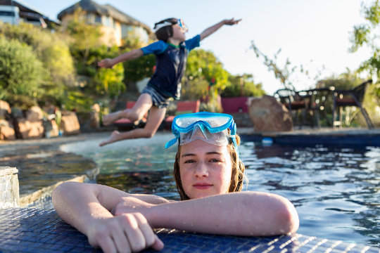 5 year old boy leaping into pool, sister in foreground, Todos Santos. Mexico