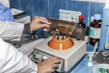 A scientist regulates an agitator machine for test tubes in a lab