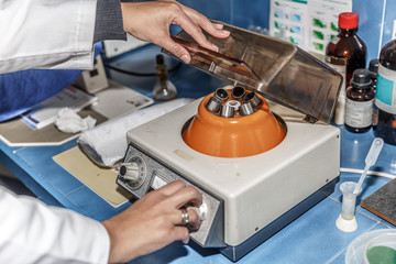 A scientific woman prepares and adjusts a stirring machine for test tubes in a lab
